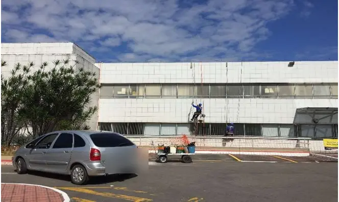 Profissional em acesso por corda executando lavagem e pintura da fachada do Vitória Apart Hospital